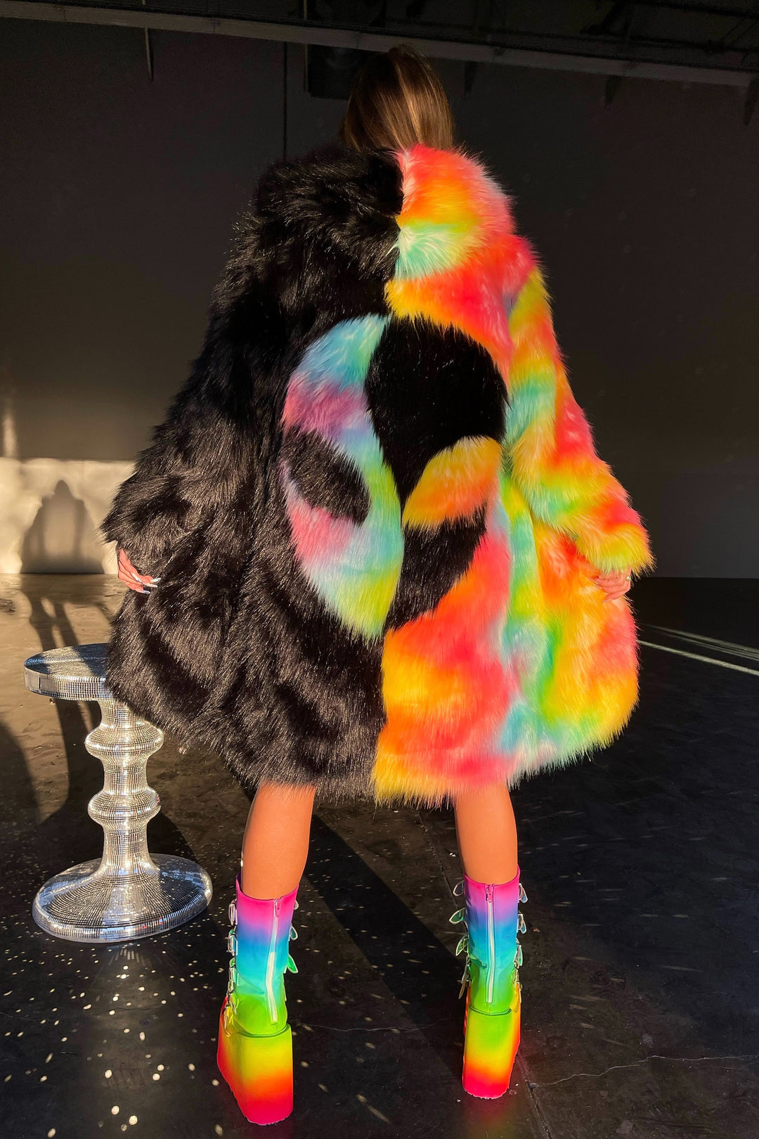 Area 51 alt text: Area 51 Alien face coat black and neon rainbow faux fur by Space island. Spvce Island is a wearable art collective featuring festival fashion, rave wear, club wear and streetwear. Buy coats, jackets, platform boots, gogo boots, rainbow platform sneakers, holographic sandals, shoes, burning man goggles, crystal chokers, holographic corsets, joggers, rave bottoms, bikinis, harnesses, bondage and more. 